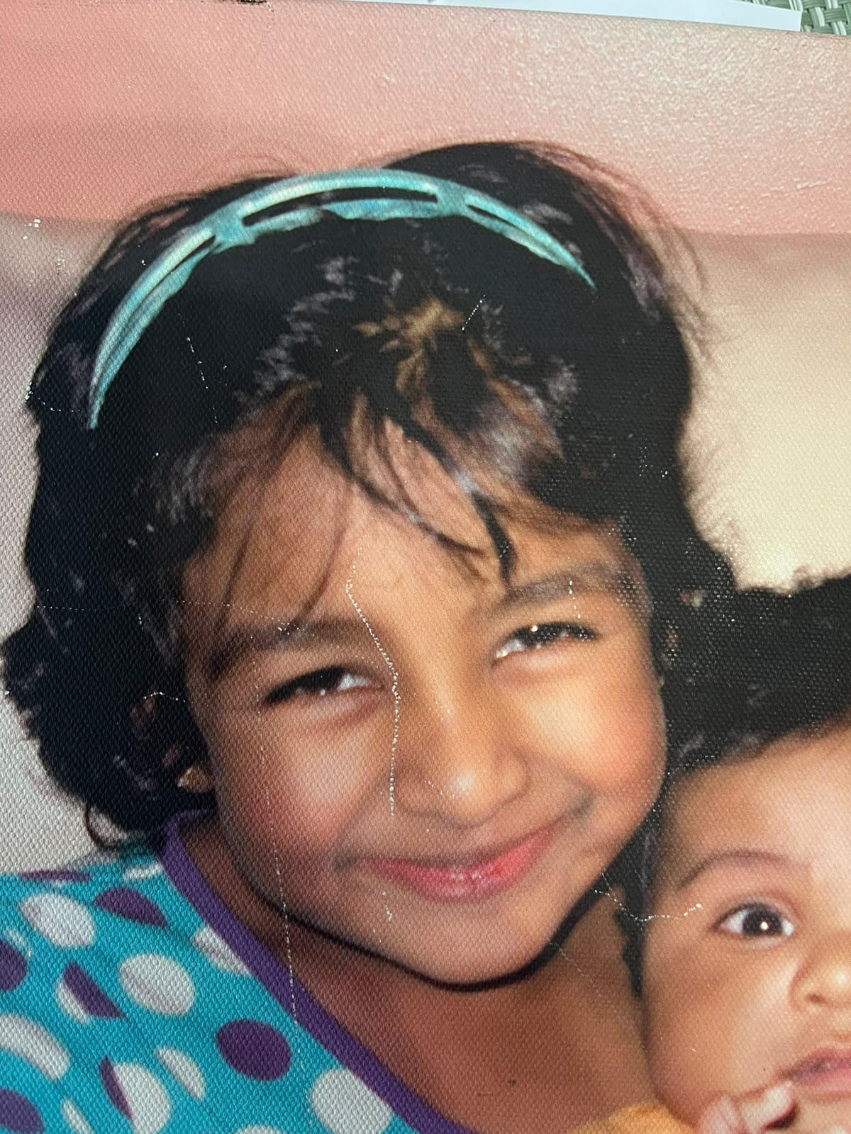 Toddler Kaysh with a headband, holding her baby sibling