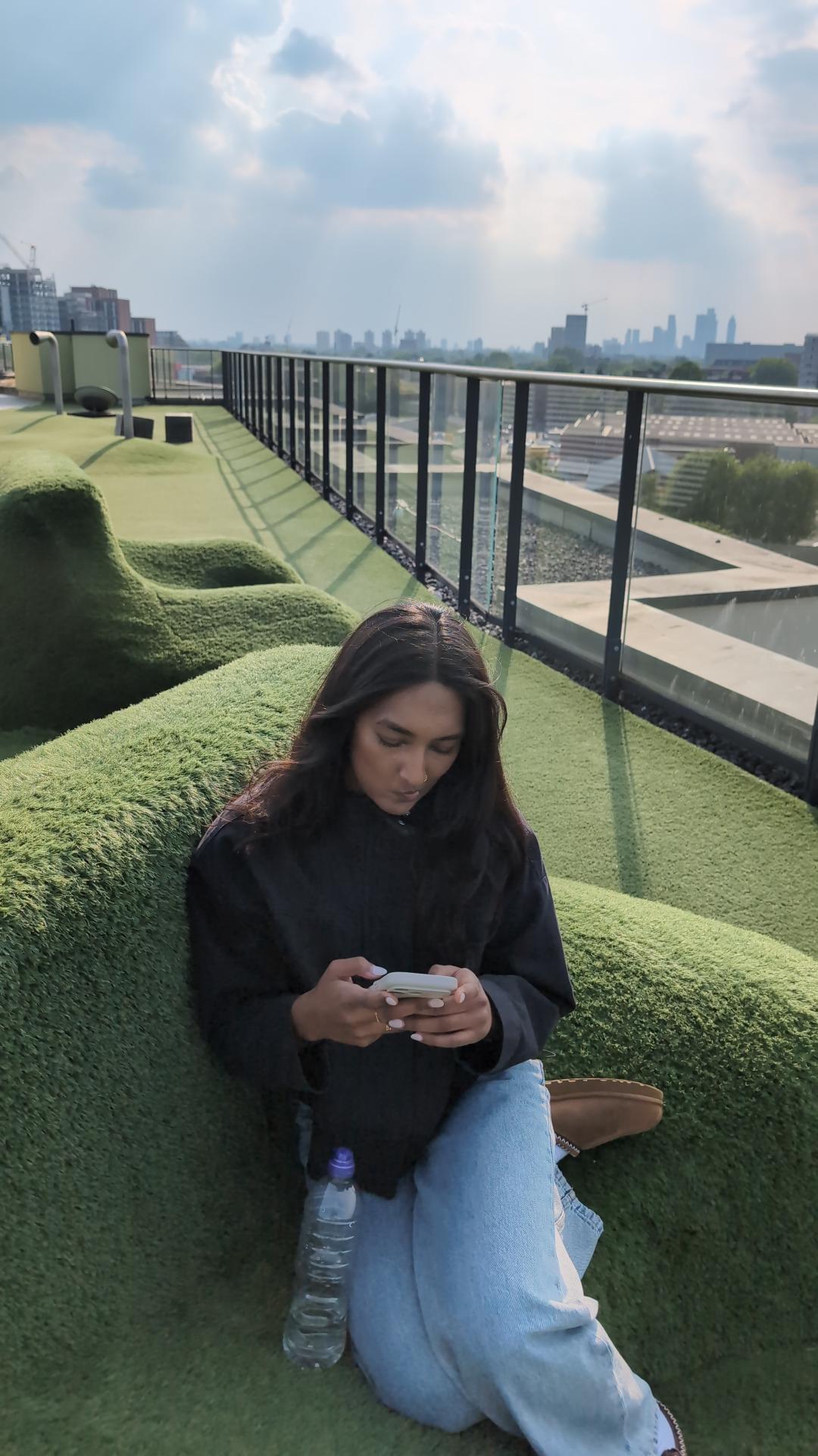 Kaysh sitting on a rooftop terrace with a city skyline behind her